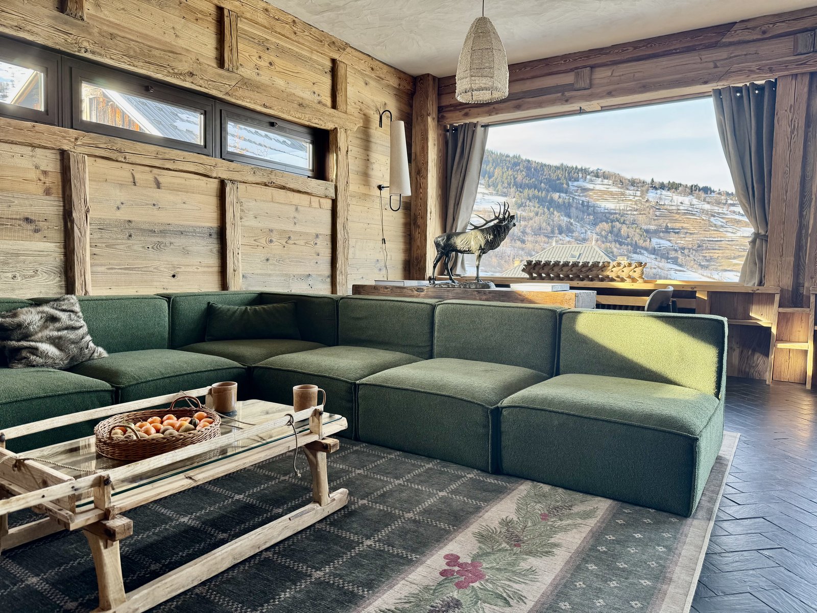 Salon du chalet Arpian, canapé bouclé vert, vue sur Valmorel